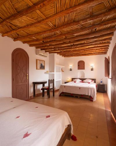 a bedroom with two beds and a wooden ceiling at Paradis Nomade in Azrarag
