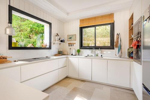 a kitchen with white cabinets and a window at Villa Lilas Cap-Ferret in Lège-Cap-Ferret