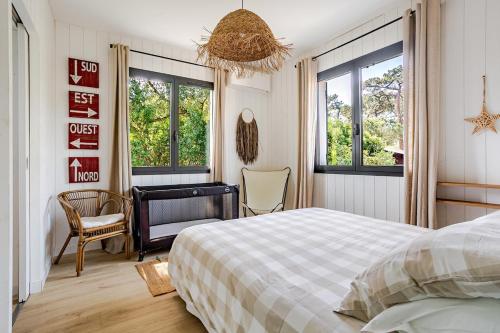 a bedroom with a bed and a desk and windows at Villa Lilas Cap-Ferret in Lège-Cap-Ferret