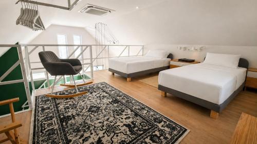 a bedroom with two beds and a chair and a rug at Holzhaus Sikonda in Komló
