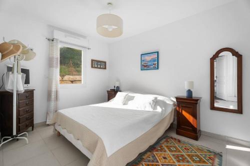 a white bedroom with a bed and a mirror at Grand T2 proche plage in Six-Fours-les-Plages