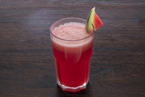 a glass of red juice with a piece of fruit at Hotel 88 Kedungsari - Kedungdoro By WH in Surabaya