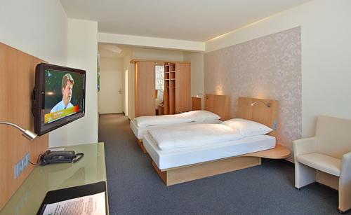 a hotel room with two beds and a flat screen tv at Thöles*** Am Allerpark Verden in Verden