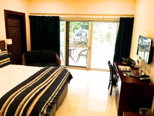 a bedroom with a bed and a desk and a sliding glass door at Madang Resort in Madang