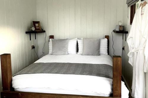 a bedroom with a bed with white sheets and pillows at Trethowels Grey Hidden hut in St Austell