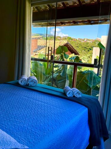 a bedroom with a window with a blue bed with a view at Serra do Cipó Casa Baru in Santana do Riacho