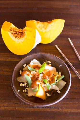 un bol de nourriture sur une table en bois avec une papaye tranchée dans l'établissement Suarga Padang Padang, à Uluwatu