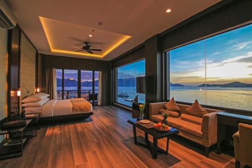 a bedroom with a bed and a couch and large windows at Two Seasons Coron Bayside Hotel in Coron