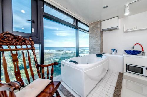 bagno con vasca e ampia finestra di Olleyo Resort a Seogwipo