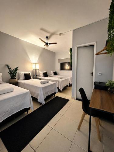 a hotel room with three beds and a ceiling fan at Hotel Santorini in Trindade