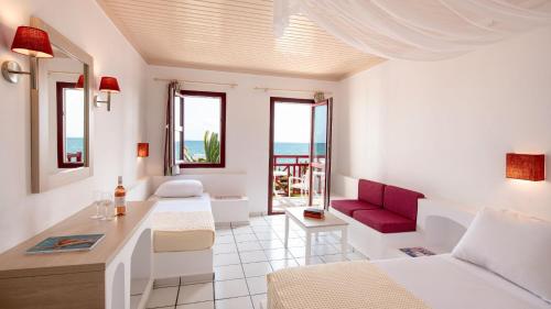 a white room with a bed and a table and some windows at Canvas by Mitsis Cretan Village in Hersonissos