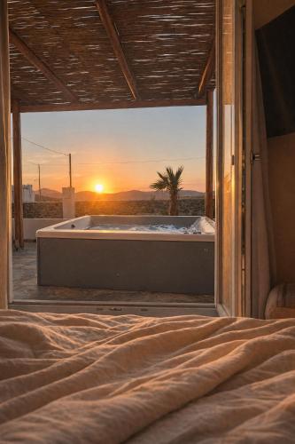 a bed in a bedroom with a view of the sunset at Kyma Sunset Suite w Prvate Jacuzzi in Paros National Airport