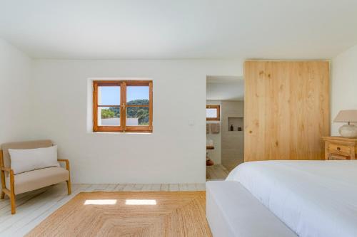 a white bedroom with a bed and a chair at Quinta Javali in Aljezur