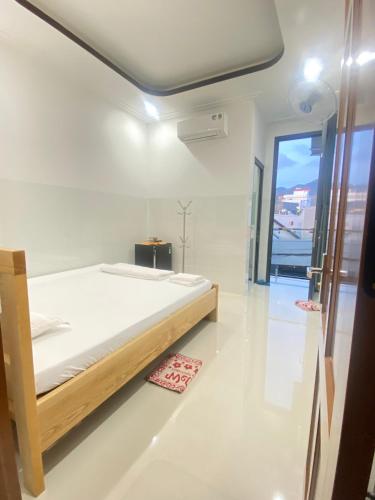 a white bedroom with a bed and a window at Nhà Nghỉ THÀNH LỘC in Long Hai