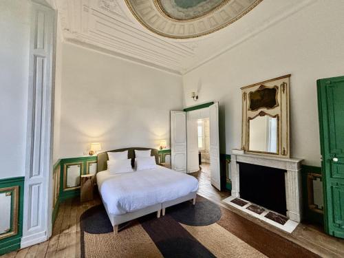 a bedroom with a white bed and a fireplace at Château Royal de Benays - Hôtel in Benais