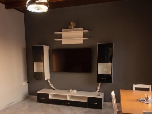 a living room with a table and a tv on a wall at Apartment Vergina in Áyioi Dhéka