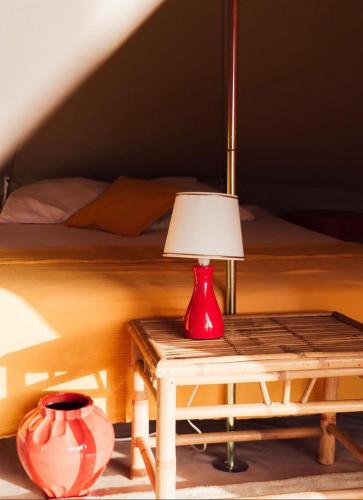 a red lamp sitting on a table next to a bed at Glamping Spot - Penmarch in Penmarch