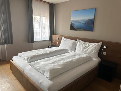 a bedroom with a large bed with white sheets and pillows at Hotel Bären in Rothenburg