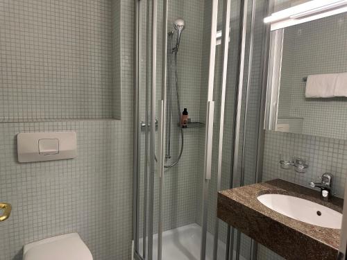 a bathroom with a shower and a toilet and a sink at Hotel Bären in Rothenburg