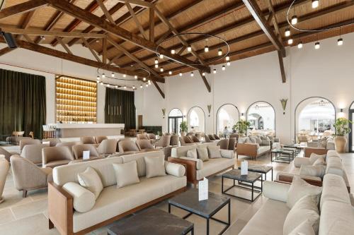 a large lobby with couches and tables and windows at Hotel Best Village Chipiona in Costa Ballena