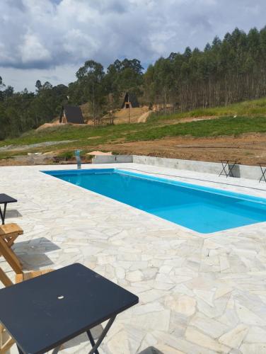 a swimming pool with a table and chairs on a patio at Be Happy Park Piracaia in Piracaia