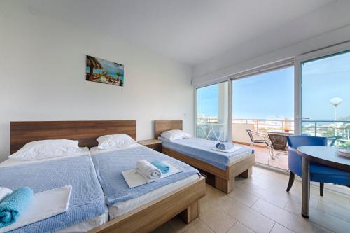 a bedroom with two beds and a table and a balcony at Vila Pepic in Dobra Voda