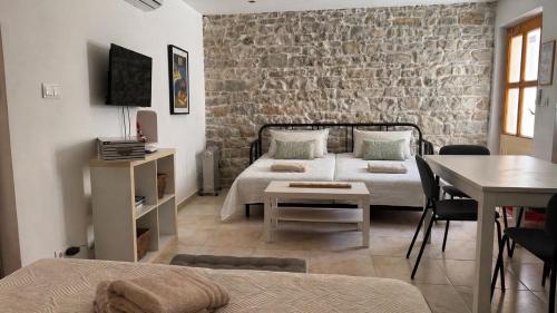 a bedroom with two beds and a brick wall at Stone house Olsavinia close to the beach in Kaštela