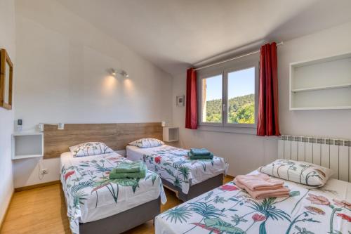 a room with two beds and a window at Les Pénates De Mélilotte in Clermont-lʼHérault