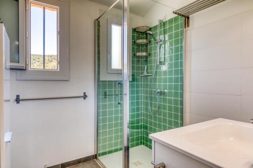 a bathroom with a green tiled shower and a sink at Les Pénates De Mélilotte in Clermont-lʼHérault