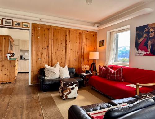 a living room with a red couch and leather chairs at Villa ai noci in Carano