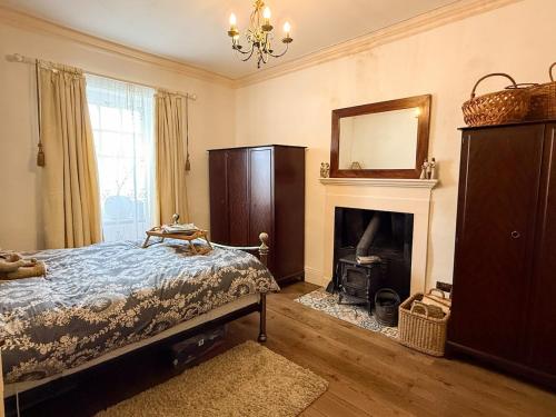 a bedroom with a bed and a fireplace and a mirror at Wingrove Cottage - Sleeps 8 in Morland