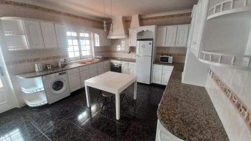 a white kitchen with a table and a white refrigerator at Casa Pascoal in Ribeira Grande