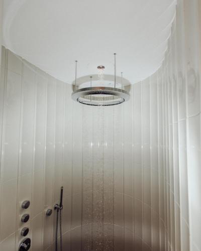 a bathroom with a shower and a chandelier at Augarten Art Hotel, a Member of Design Hotels in Graz