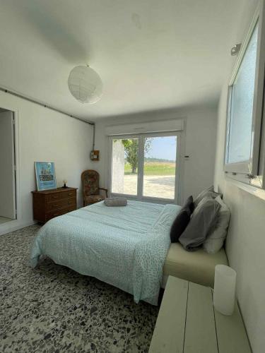 a bedroom with a bed and a large window at Gîte Le Bédat in Puycasquier