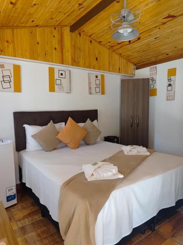 a bedroom with a large white bed with a ceiling at Pousada irmãos Oliveira in Lindóia