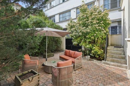 a patio with a table and chairs and an umbrella at Loft Fraternité in Bagnolet