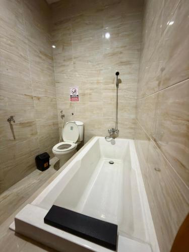 a white bath tub in a bathroom with a toilet at KalaKoala Hostel in Malang