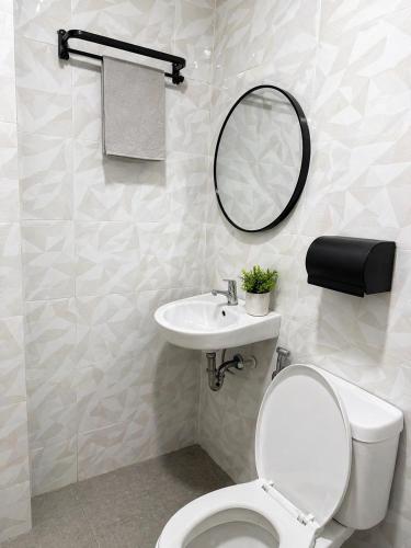 a bathroom with a toilet and a sink and a mirror at The Beach House by SYNCO in Lubong