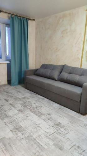 a couch in a living room with a blue curtain at Подобово Центр in Konotop