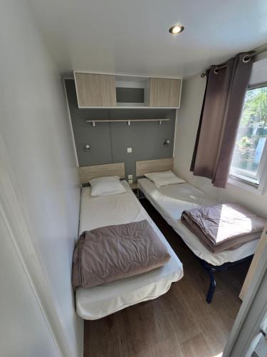 a small room with two beds and a window at camping la plage de l'orb in Cessenon