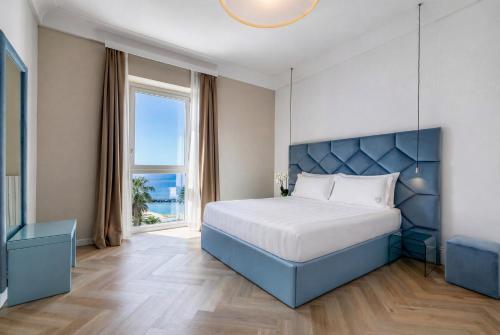 a bedroom with a bed and a large window at Miramare The Palace Resort in Sanremo