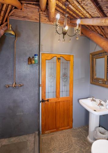 a bathroom with a wooden door and a sink at Duivenvlugt Loft in Stilbaai