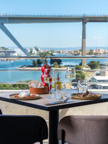 a table with two plates of food and wine glasses at Golden Tulip Hotel & Rooftop Martigues Provence in Martigues
