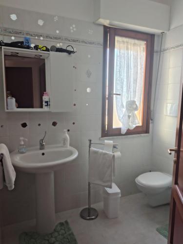 a bathroom with a sink and a toilet and a window at "Da Carla e Sandro"- Appartamento con parcheggio privato in Quartucciu