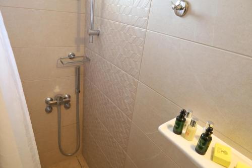 a bathroom with a shower and a sink with bottles on it at G. Kiapekou in Loutra Edipsou