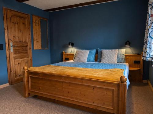 a bedroom with a large wooden bed with blue walls at Pension ElbeStay in Königstein an der Elbe