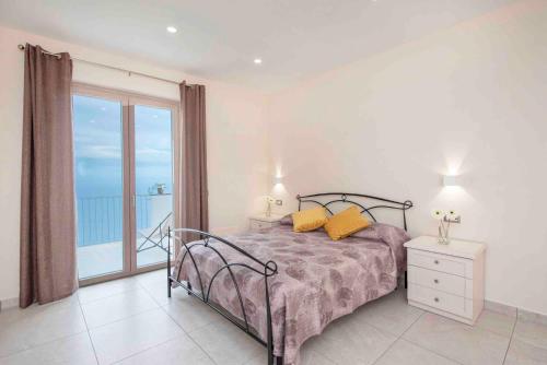 a bedroom with a bed with yellow pillows and a balcony at Coastal Escape, Amalfi in San Lazzaro Agerola