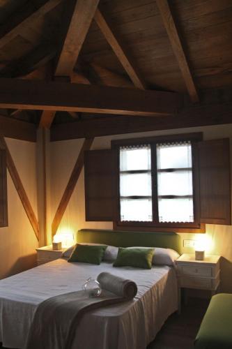 a bedroom with a large bed with two windows at Mendiko Baserria in Amurrio