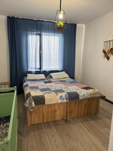 a bedroom with a bed with a blue curtain and a window at The Bay Area in Cholpon-Ata