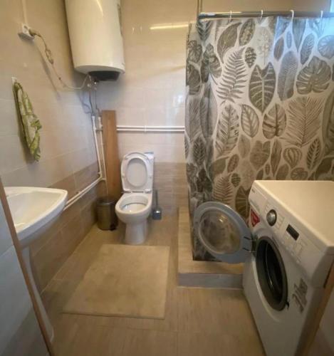 a bathroom with a toilet and a washing machine at The Bay Area in Cholpon-Ata